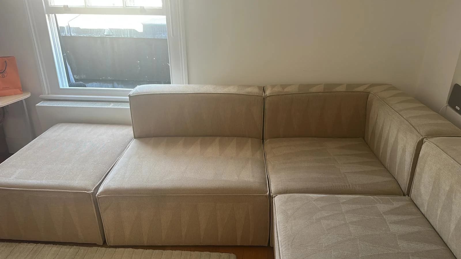 Beige fabric corner sofa with broad cushions and stitched back panels, from OneGo Cleaning Masters sofa cleaning work.